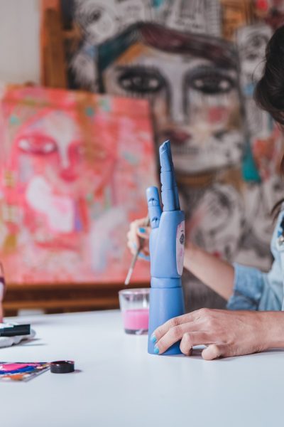 Young artist painting wood art piece inside art home studio atelier - Focus on right hand